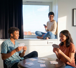 Three people relaxing in a room and playing cards