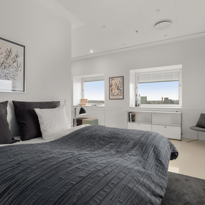 Bedroom with double bed, dark grey bedspread and open shelving unit