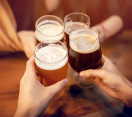 Flere hænder skåler med fyldte ølglas