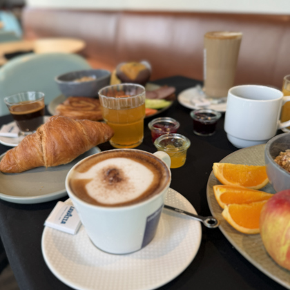 Cup of coffee with breakfast including bread and fruit