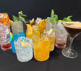 Urval av färgglada cocktails och drinkar med is och färsk garnering.