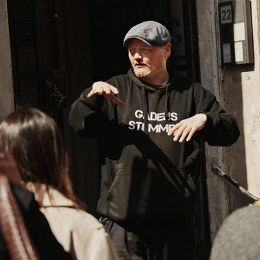 A guide explaining something in front of a building.