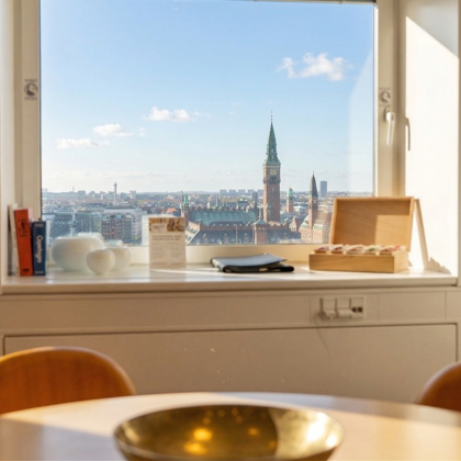Udsigt til Rådhustårnet gennem vindue i lokale med gule stole