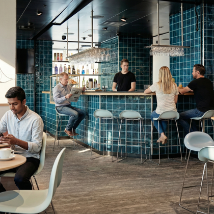 Gæster sidder i barområde med drinks i moderne café