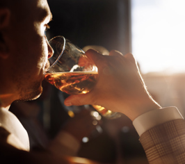 Person drikker øl fra et glas i profil